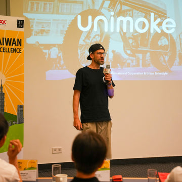 a man standing on the stage to have a great presentation of "unimoke", which is about e-bike in Taiwan