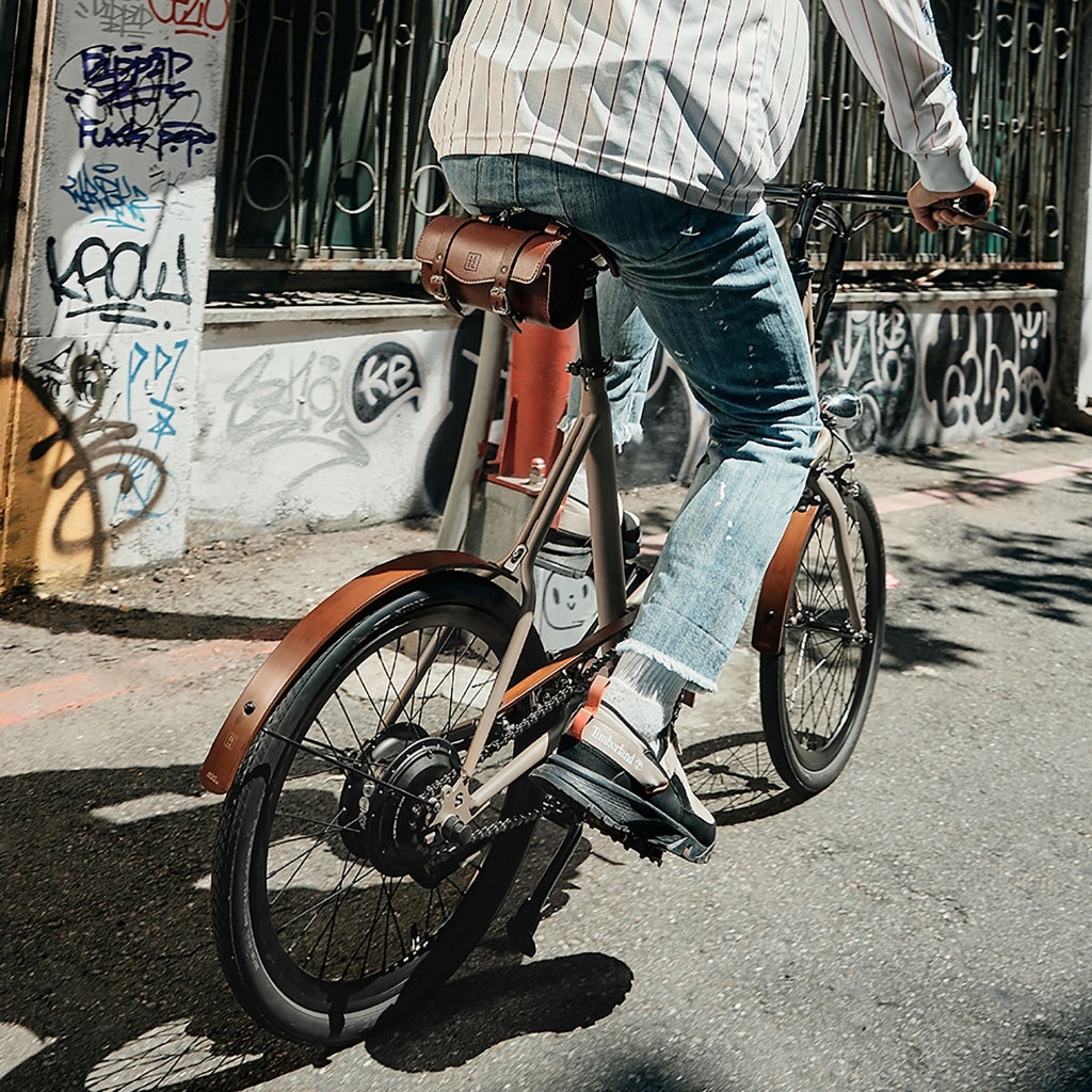 一名男子在街上騎著 SEic miniu 山貓杏駝棕，隨車配備木頭泥除及鍊蓋組，增加騎行體驗，並可安裝多款客製化配件