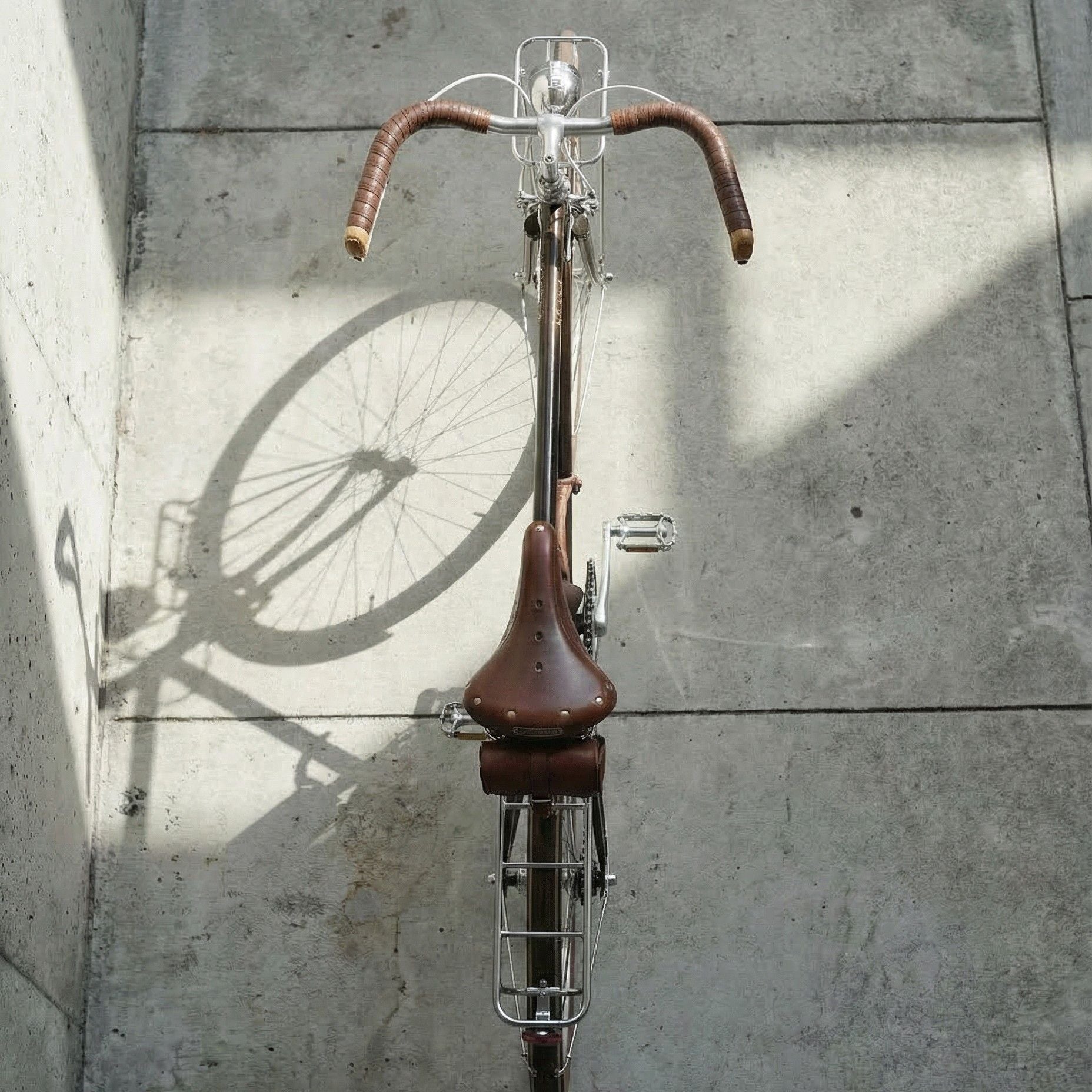 瑞士復古城市鋼管自行車俯視角度照，真皮把帶、彈簧式皮革座墊與前後貨架配置，展現經典比例與全配備城市車設定。